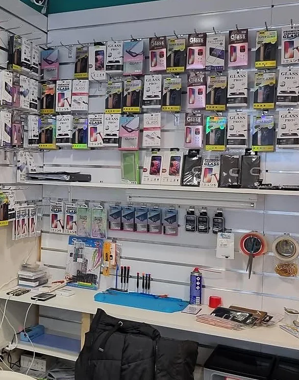 De werkbank in de winkel, met gereedschap en een wand vol screenprotectors